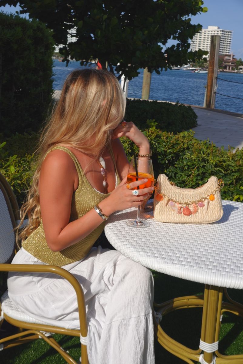 Shell rings and charm bag at a café table overlooking the water