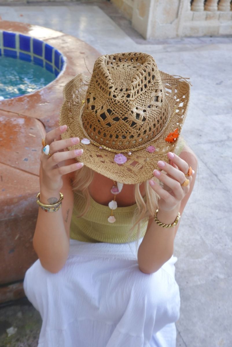 Model hiding behind a straw cowboy hat trimmed with shells