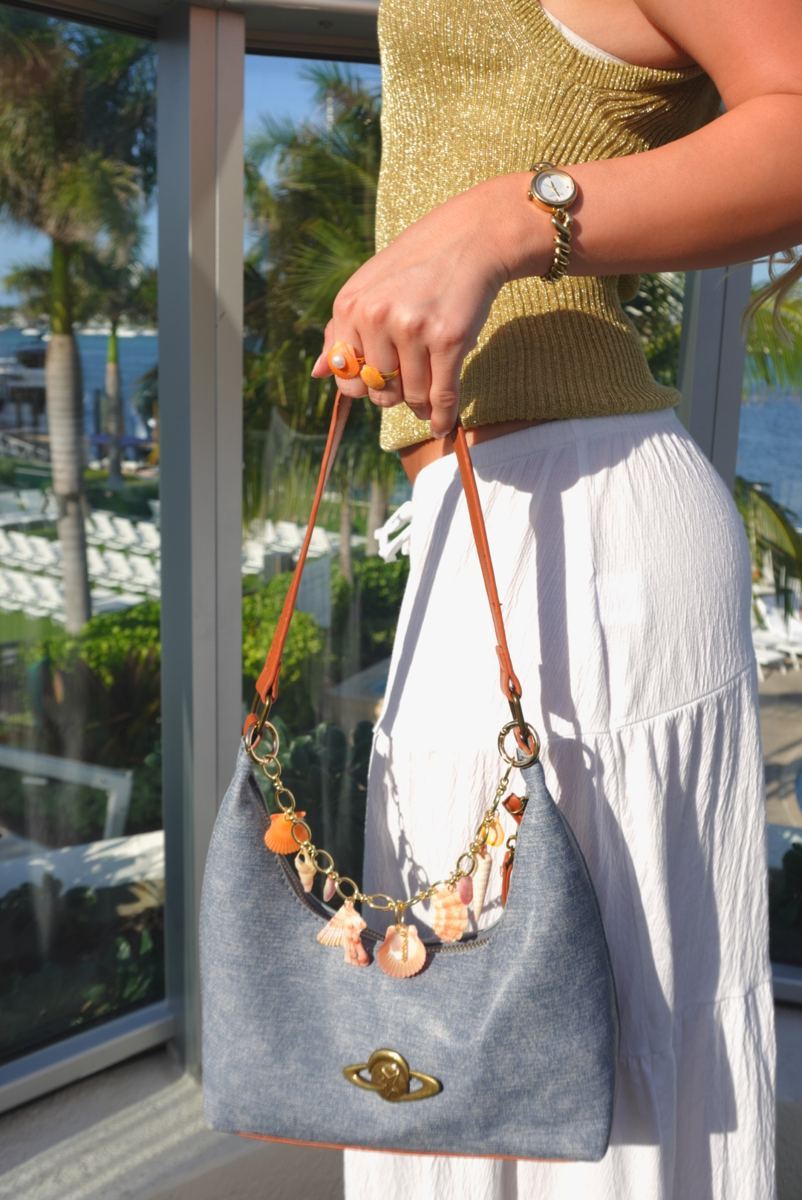 Gold shell charm on a denim shoulder bag with orange shell rings