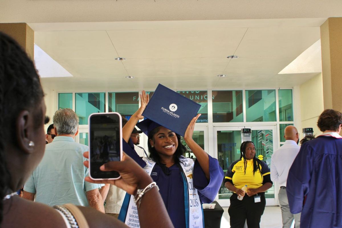 Graduate holding her diploma above her head outside the Student Union