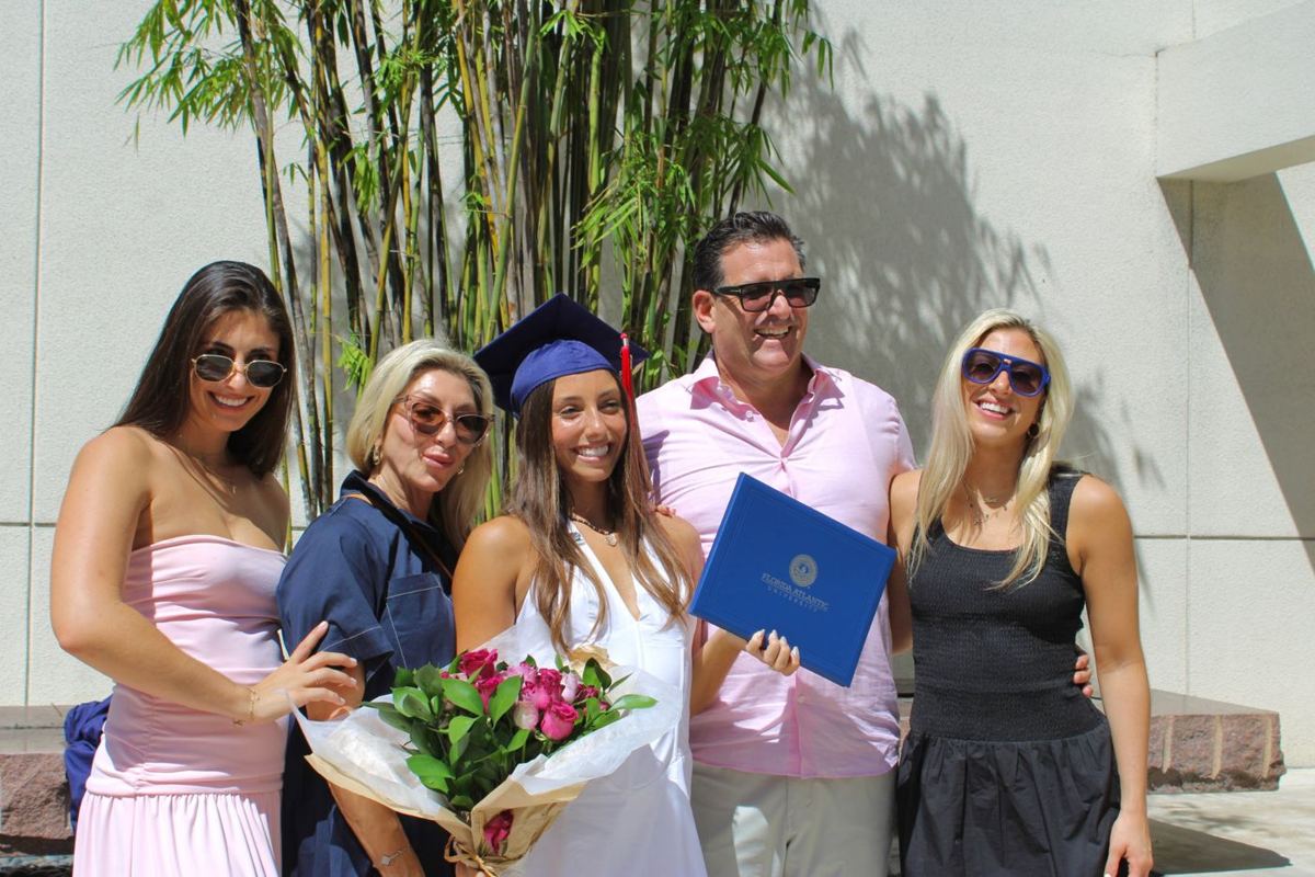 Graduate celebrating with family holding flowers and her diploma